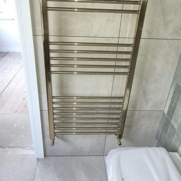 Brushed brass heated towel rail installation